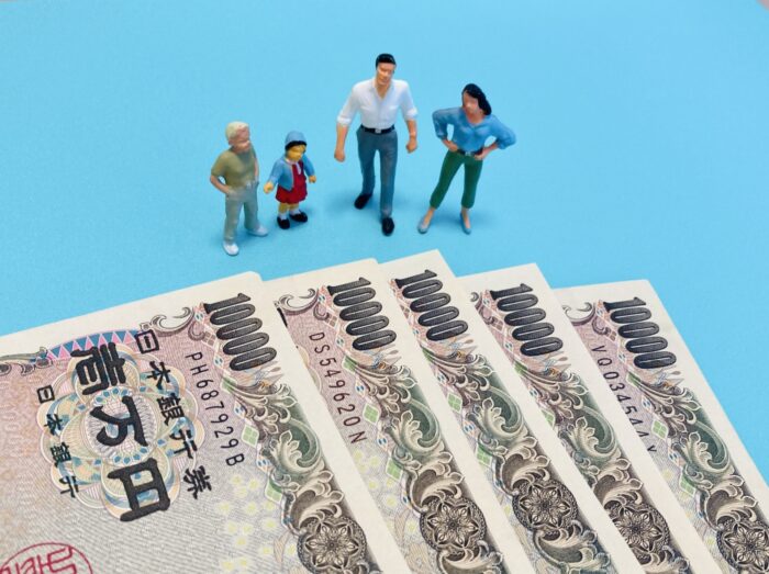 親子間の金銭貸借をイメージした1万円札と家族のミニチュア人形