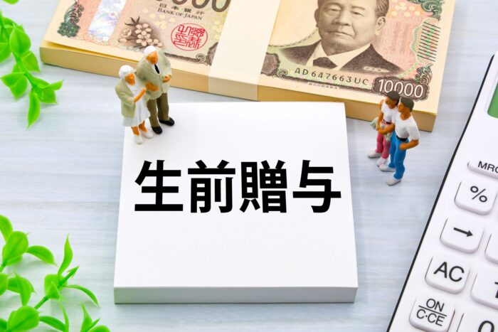 生前贈与と書かれたメモと1万円札・電卓・家族のミニチュア